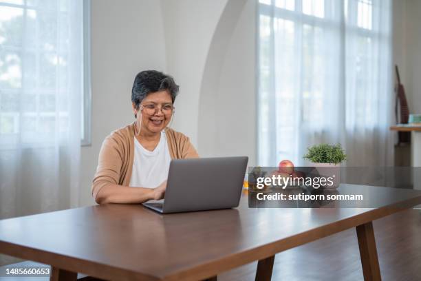 asian senior woman use labtop and smiling - comminuted fracture stock pictures, royalty-free photos & images