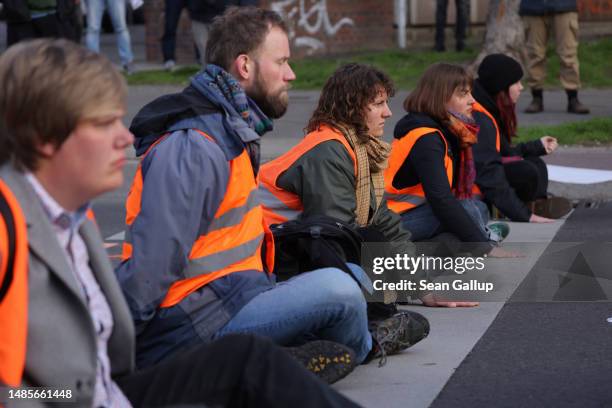 Climate activists from Last Generation , some of whom have glued their hands to the asphalt, block traffic at an intersection on Landsberger Allee on...