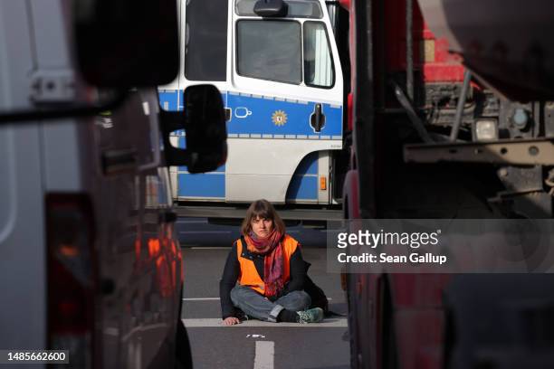 Climate activist from Last Generation sits with one hand super glued to the asphalt as she and others block traffic at an intersection on Landsberger...