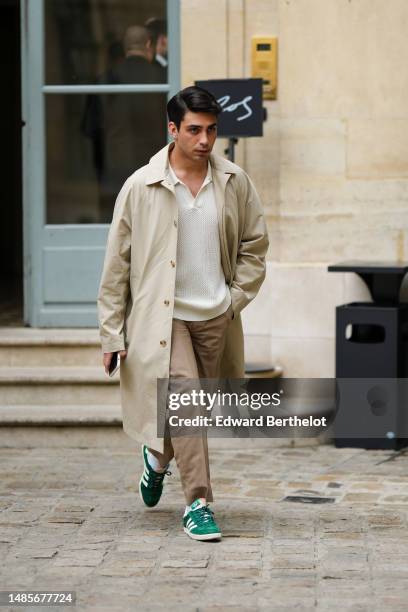 Guest wears a white mesh / cut-out pattern V-neck / polo neck oversized shirt, a beige buttoned long trench coat, brown suit pants, green suede and...