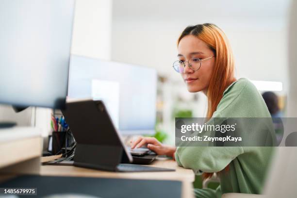 young woman working on multiple screens at home office - datawetenschapper stockfoto's en -beelden