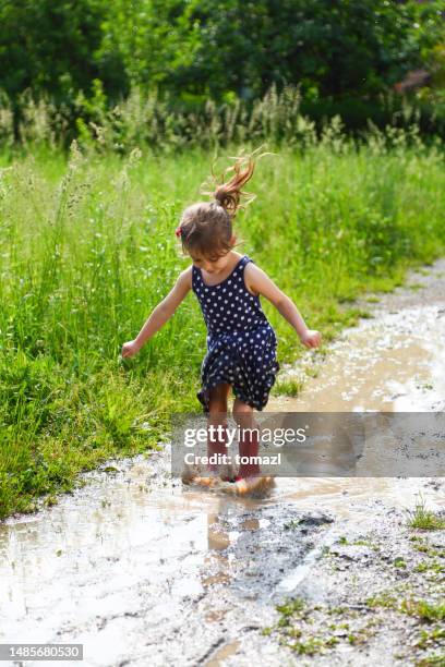 child enjoying a big puddle of mudd - kid stomping feet stock pictures, royalty-free photos & images