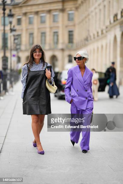 Guest wears silver metallic sunglasses, a navy blue and white striped print pattern cotton shirt, a black shiny leather tank-top / short dress, a...
