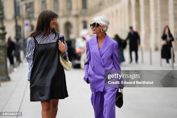 Guest wears silver metallic sunglasses, a navy blue and white striped print pattern cotton shirt, a black shiny leather tank-top / short dress, a...