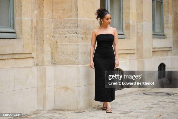 Lena Mahfouf wears gold large earrings, a black embossed striped pattern / shoulder-off / long slit / split dress, black shiny strappy leather small...