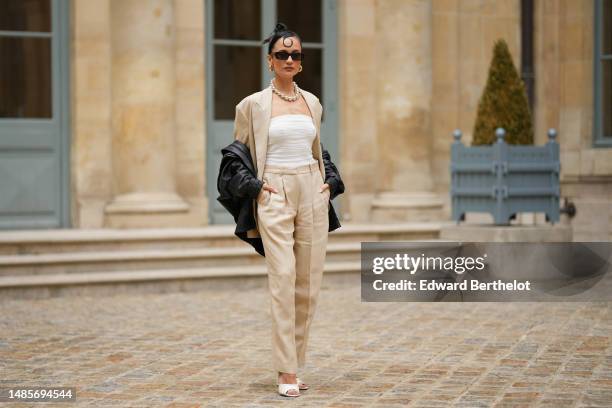 Anna Rosa Vitiello wears black sunglasses, gold large earrings, a silver large pearls necklace, a white embossed striped pattern shoulder-off body...