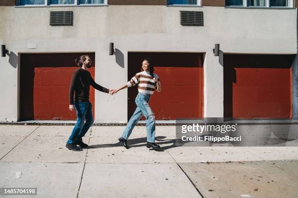 an hipster couple is running together on the sidewalk in brooklyn - dragged shutter stock pictures, royalty-free photos & images