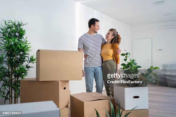 young caucasian couple, taking a moment in their new apartment - heteroseksueel koppel stockfoto's en -beelden