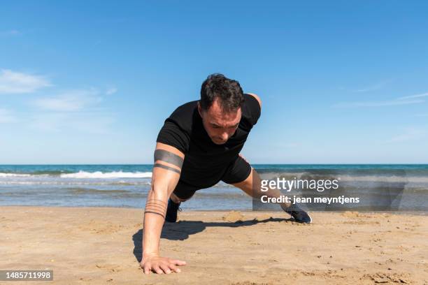 mature man doing one arm push-ups at the beach - costa_del_azahar stock pictures, royalty-free photos & images