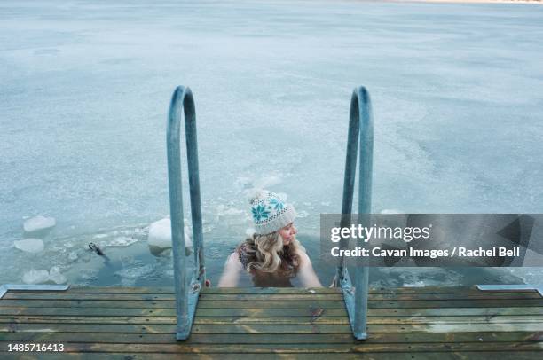 woman taking a dip in the frozen baltic sea in scandinavia - eis baden stock-fotos und bilder