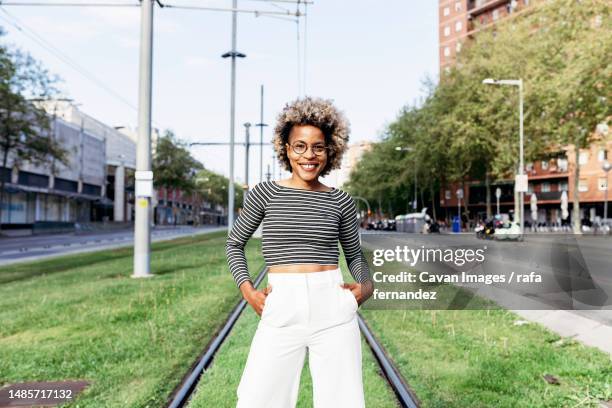 portrait of afro-american woman posing in the street with white pants - white pants stock pictures, royalty-free photos & images