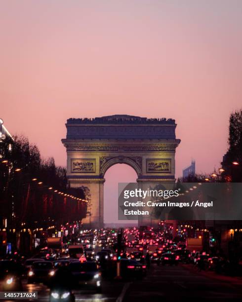 view of arc de triomphe over sunset from champs elysees - シャンゼリゼ通り ストックフォトと画像