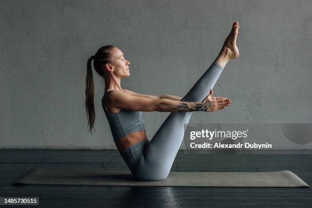 beautiful young woman practicing yoga in yoga studio indoors - metodo pilates foto e immagini stock