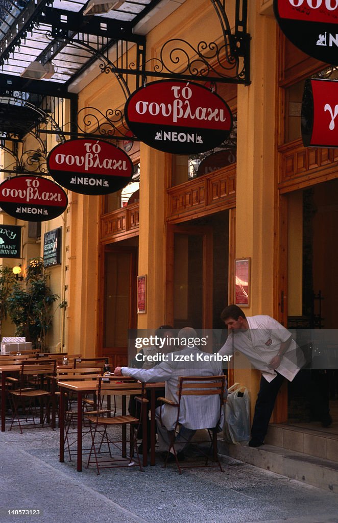 Two men meet at an outdoor cafe in Omonia.