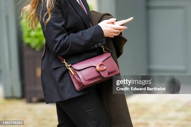 Guest wears a white t-shirt, a black striped print pattern blazer jacket, matching black striped print pattern suit pants, a burgundy shiny leather...