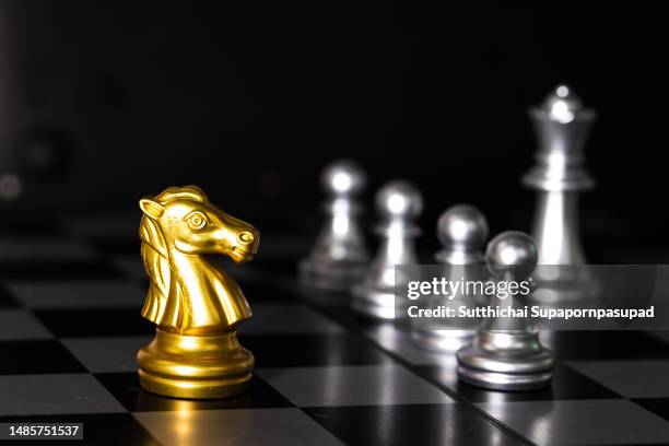gold and silver colored chess king and horse pieces checkmate on the chessboard with black background. - chess horse fotografías e imágenes de stock