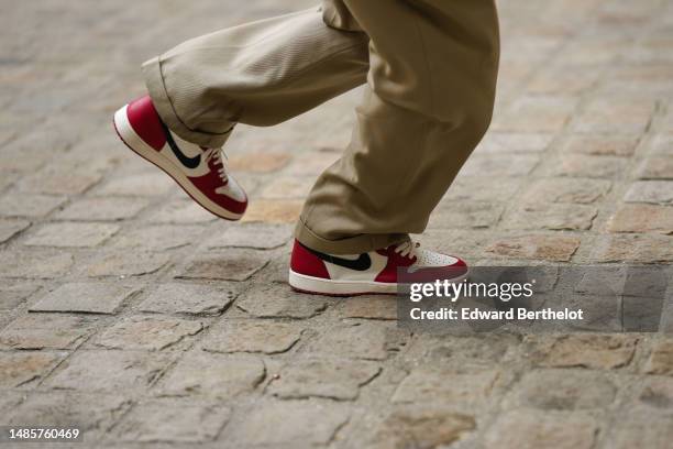 Guest wears khaki beige pants, white and red with black logo shiny leather Air Force One sneakers from Nike, outside the COS show, on April 26, 2023...