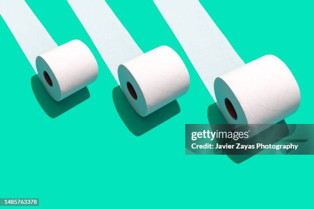 three toilet rolls on green background - cardboard roll stock pictures, royalty-free photos & images