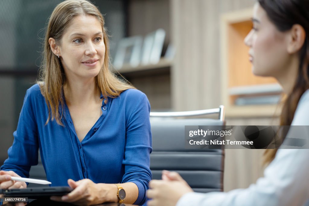 Tell Me About Your Past Work Experience. Human Resources Manager conducting an interviewing with a woman for new staff to support business operations in a business office.