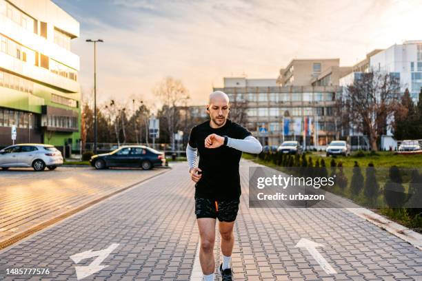 athleten, die ihre fitnessaktivität auf dem fitness-tracker überprüfen, während sie im freien laufen - pedometer stock-fotos und bilder