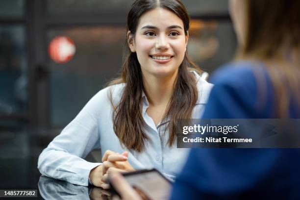 determine earning power and professional growth opportunities.  a new female employee on a job interview final round with an hr officer in a business office. - service management stockfoto's en -beelden