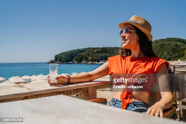 young woman drinking ouzo in the beach bar - ouzo stock pictures, royalty-free photos & images