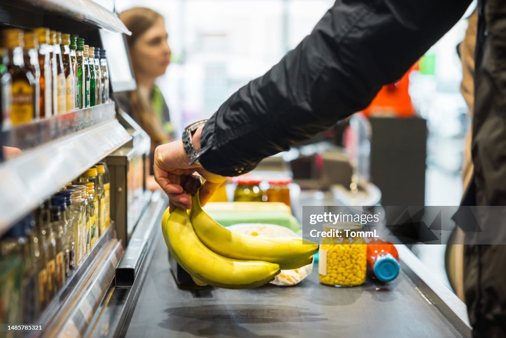 Person Putting Bananas On Conveyor At Store Checkout
