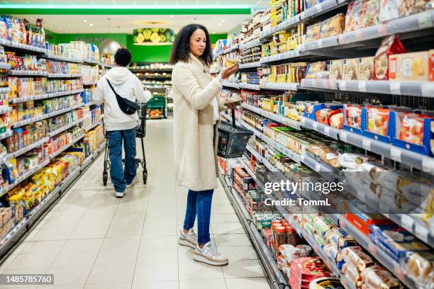 woman reading item label while grocery shopping in local supermarket - convenient store 個照片及圖片檔