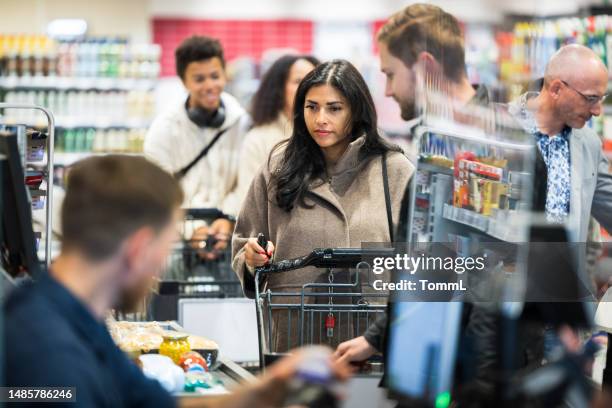 clienti in coda alla cassa nel supermercato locale - fare la fila foto e immagini stock