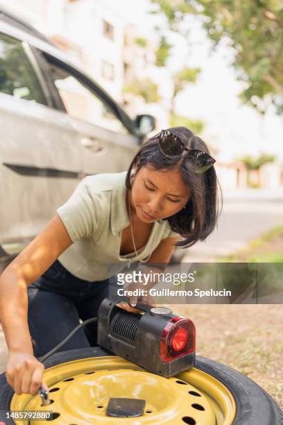 woman filling a flat tyre with air - air pump stock pictures, royalty-free photos & images