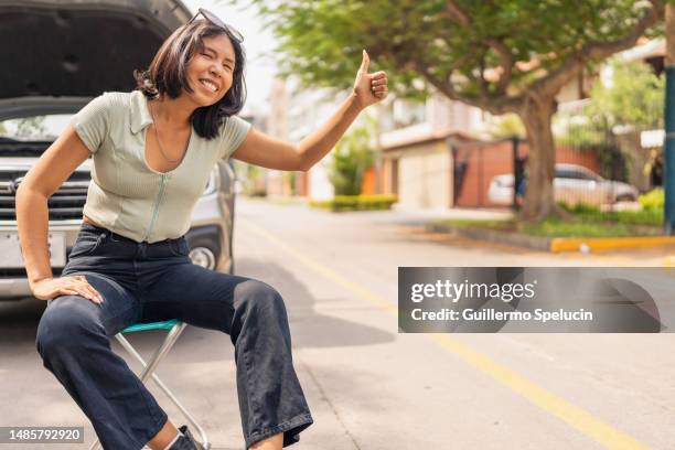 cool woman hitchhiking next to broken car - hitchhiking stock pictures, royalty-free photos & images