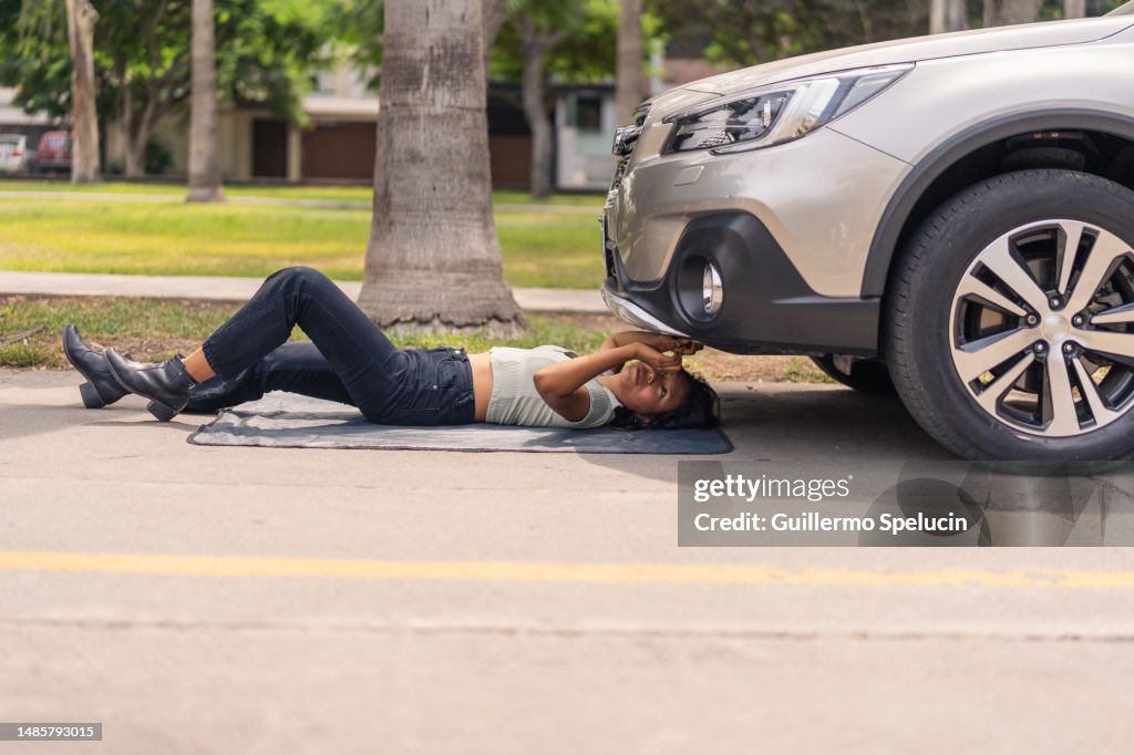 Woman lying on the floor repairing a broken car