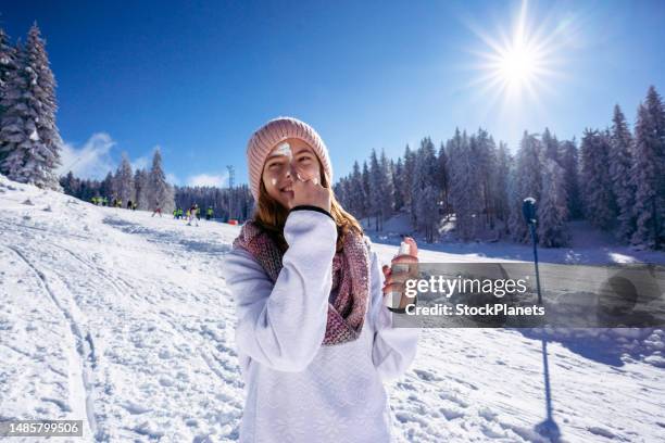 girl protecting skin applying moisturizer cream in a snowy mountain - winter skin stock pictures, royalty-free photos & images