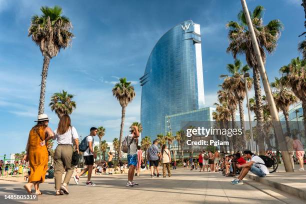 a crowd of people walk along the boardwalk of barceloneta beach in barcelona spain - la barceloneta stockfoto's en -beelden