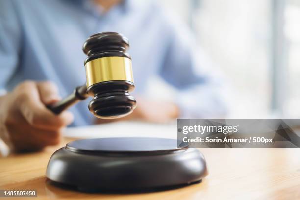 midsection of judge hammering gavel on table - auction table stock pictures, royalty-free photos & images