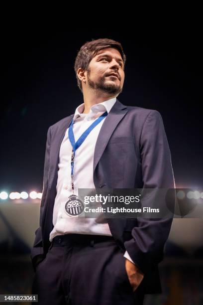 male soccer coach stands with assertive posture in a stadium while watching his team - live broadcast stock pictures, royalty-free photos & images