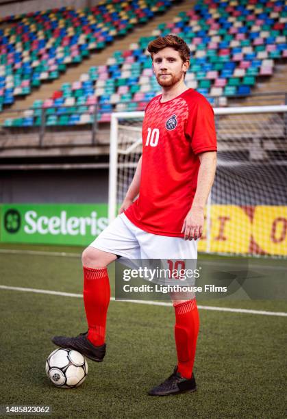 young adult male athlete confidently poses with soccer ball before professional game - shin guard stock pictures, royalty-free photos & images