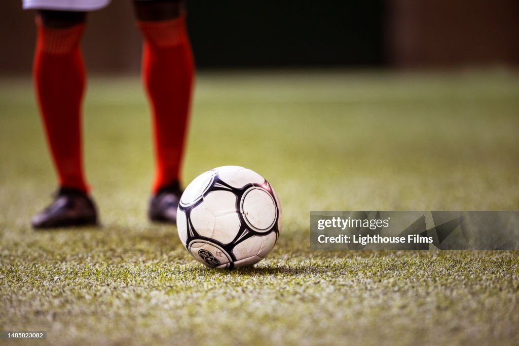 Professional soccer player prepares to strike soccer ball with his cleat on stadium field