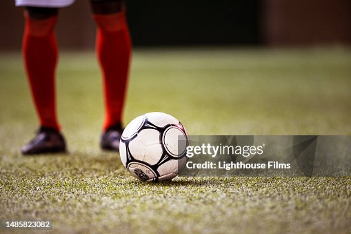 Professional soccer player prepares to strike soccer ball with his cleat on stadium field Professional soccer player prepares to strike soccer ball with his cleat on stadium field