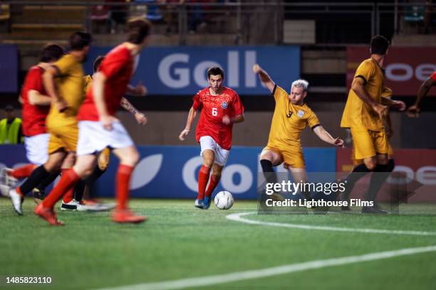 a competitive international football player attempts to keep opponent an from stealing ball as they run down field - game experience stock pictures, royalty-free photos & images