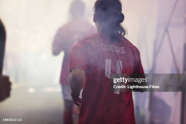 an adult male professional soccer player jogs through a fog-filled tunnel onto a large stadium for a crucial game - sports jersey back stock pictures, royalty-free photos & images