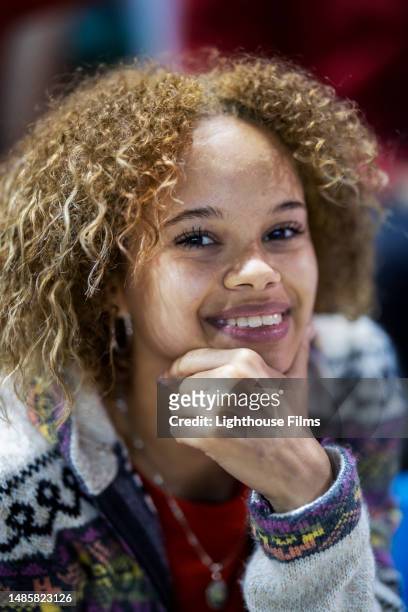 naturally beautiful young woman sits in an audience of sporting event and smiles at camera - headshots soccer stock-fotos und bilder