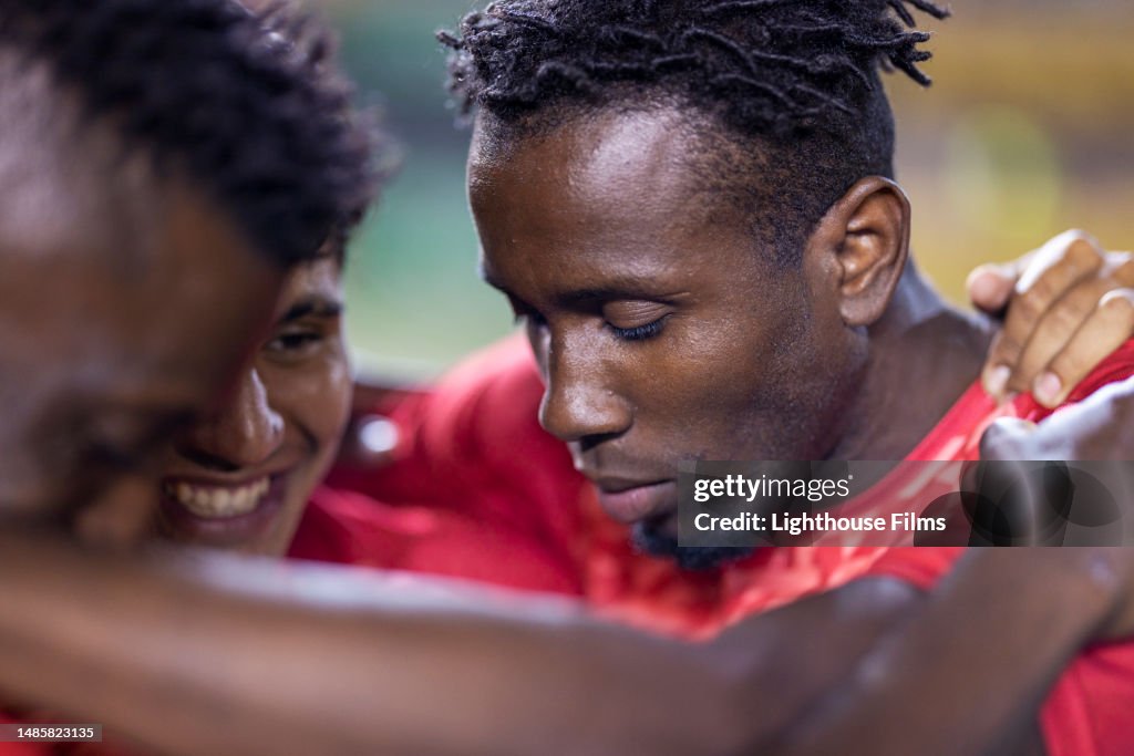 Professional adult male soccer player focuses during a team huddle to strategize during a championship game