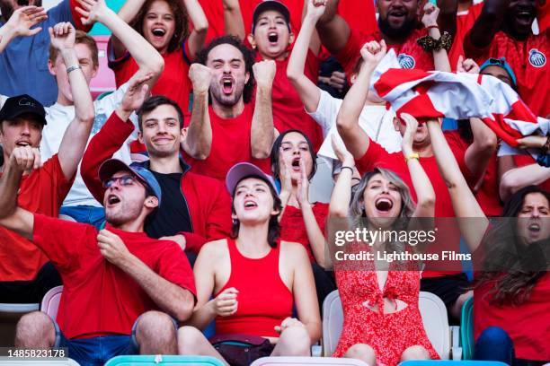 ecstatic sports fans shout in support and cheer from the stadium bleachers after their favorite team scores - bleachers stock pictures, royalty-free photos & images