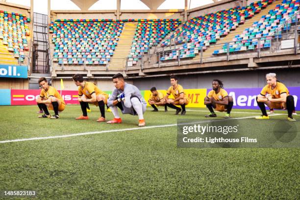 athletic male football players complete warm-up exercises to prepare for a big game - gold shoe stock pictures, royalty-free photos & images