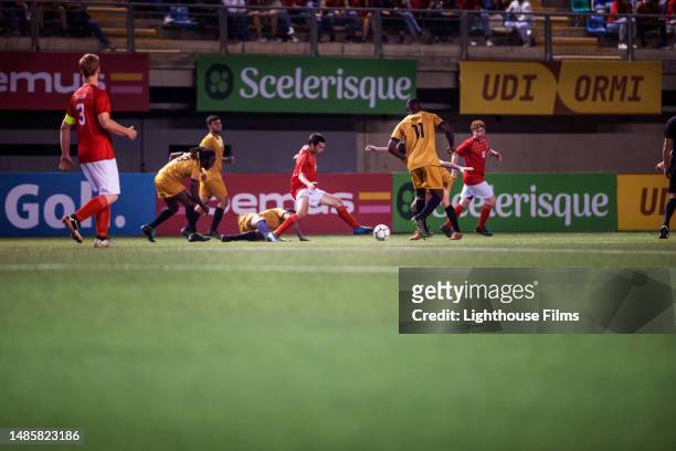 agile professional soccer player attempts to prevent opponents from stealing ball away during an international match - professional soccer team stock pictures, royalty-free photos & images