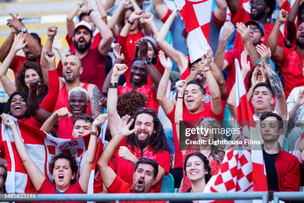 huge crowd of enthusiastic soccer fans cheer and raise  team flag up while celebrating team scoring a goal - chanting stock pictures, royalty-free photos & images