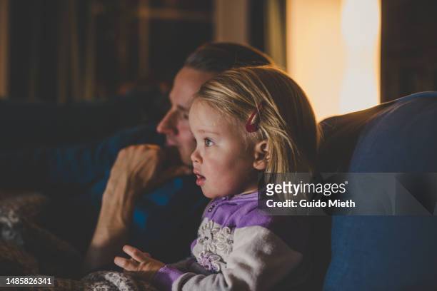father and his daughter watching tv together. - cocoon stock pictures, royalty-free photos & images