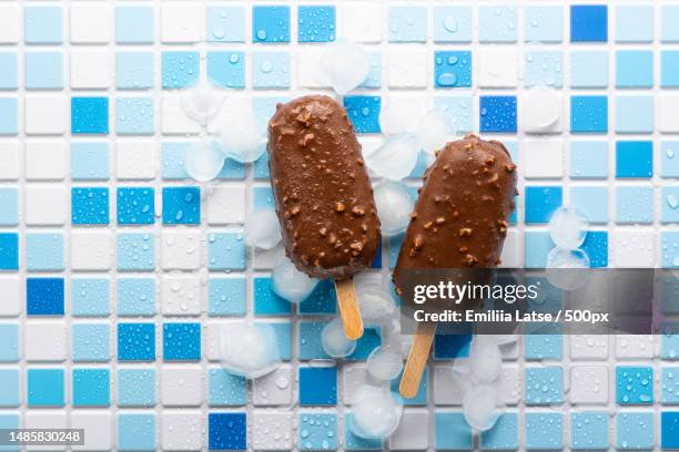 flat lay eskimo ice cream popsicles in chocolate nut glaze on ice,on a white and blue tile,russia - icing stock pictures, royalty-free photos & images