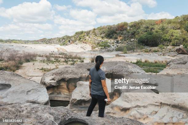 asian woman looking out at pedernales falls state park - pedernales stock pictures, royalty-free photos & images